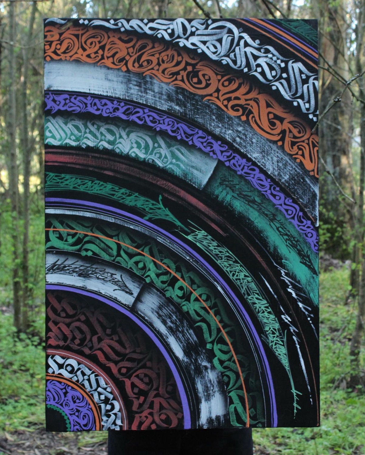 Tela com arcos concêntricos de caligrafia colorida, fotografada num bosque
