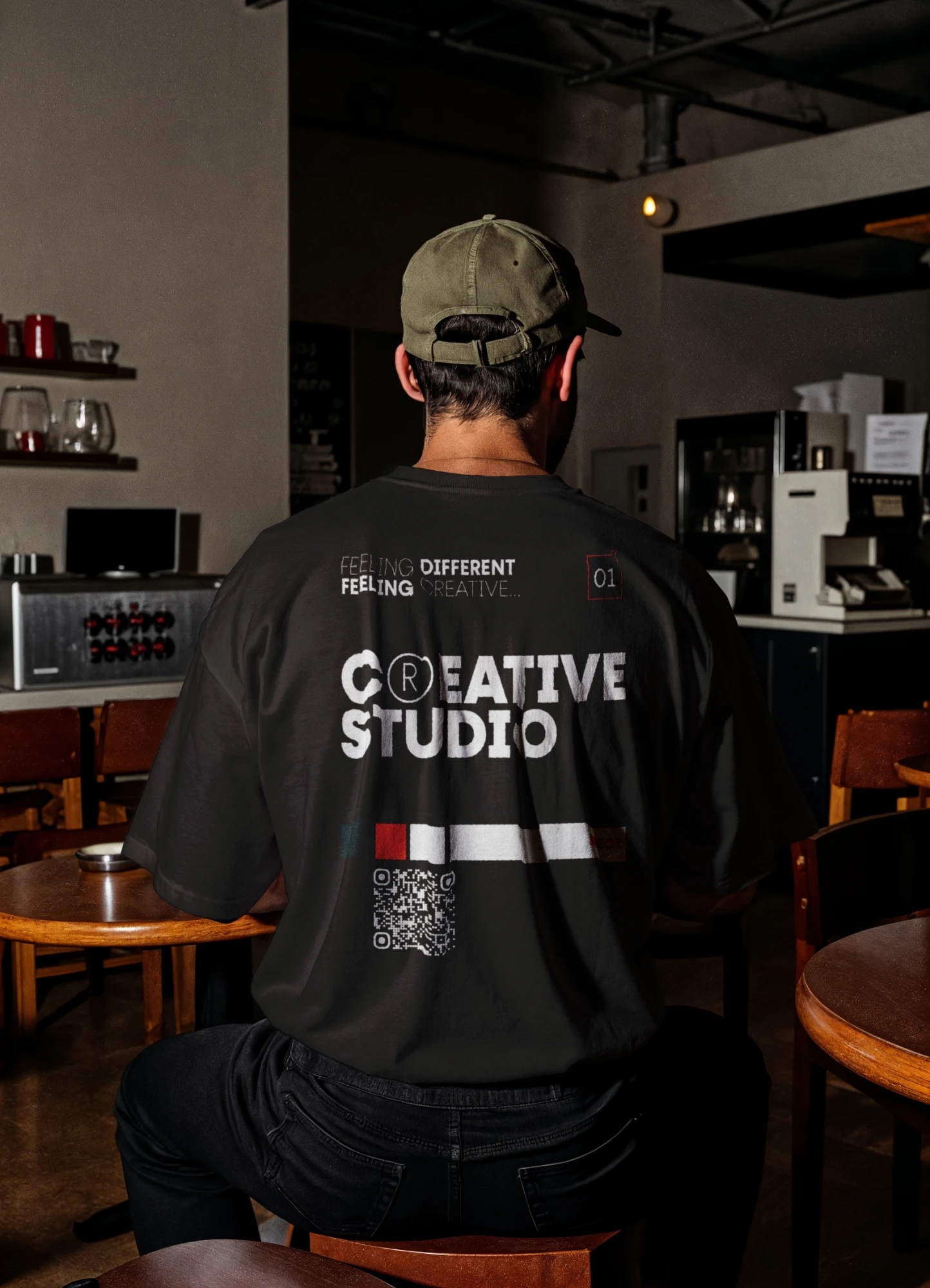 Pessoa de costas num café com t-shirt preta Creative Studio e código QR